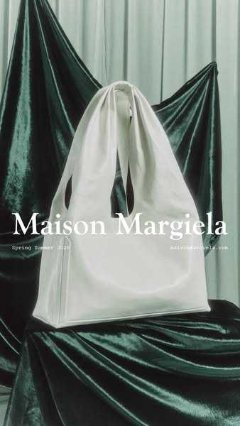 This ad features a white Maison Margiela bag set against a draped fabric background. The brand's name and website ar