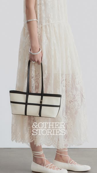 This & Other Stories ad showcases a structured tote bag, held by a model in a lace dress and ballet flats. The focus