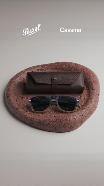 A product shot of sunglasses and their case, presented on a textured stone surface. The ad has a clean, minimalist aesth