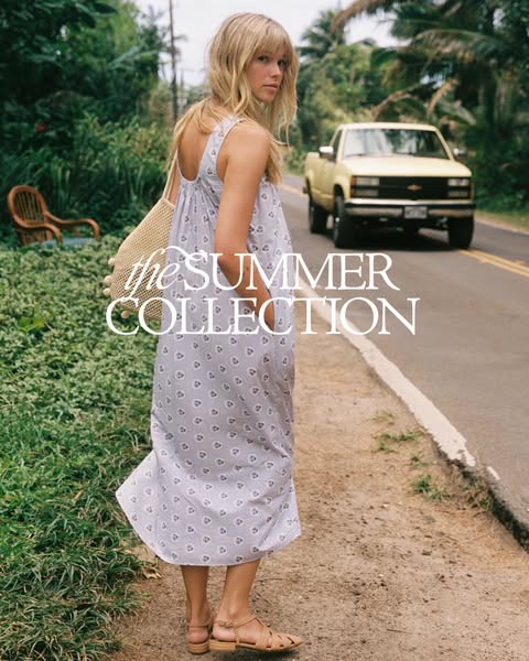This ad features a woman walking on the side of a road wearing a floral print dress from "the SUMMER COLLECTION&quo