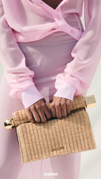 This ad features a woven handbag from Jacquemus with gold hardware and a pink background.