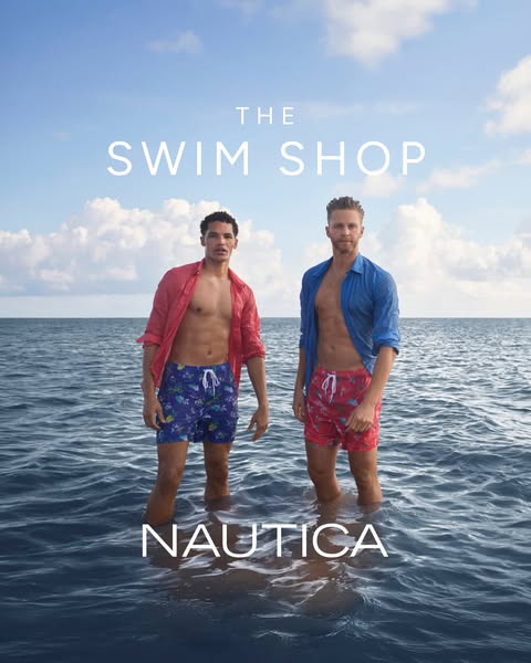 This ad showcases men's swim trunks from Nautica. Two men stand waist-deep in the ocean wearing swim trunks and unbu