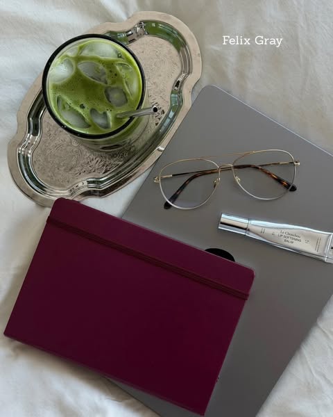 An ad showcasing a lip product in a neutral work/study environment.