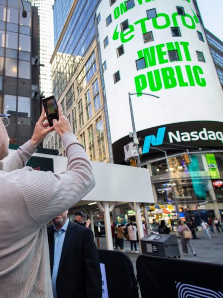 An image ad showcasing the brand eToro's presence in Times Square. It captures a moment of someone photographing the
