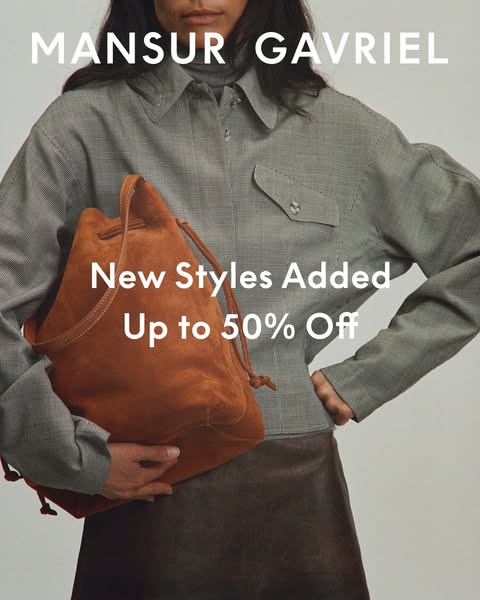 This image ad for Mansur Gavriel features a model wearing a gray patterned top and brown skirt, holding a brown suede bu