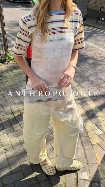 This image ad from Anthropologie features a model wearing a casual outfit that includes a white dress with lace detailin