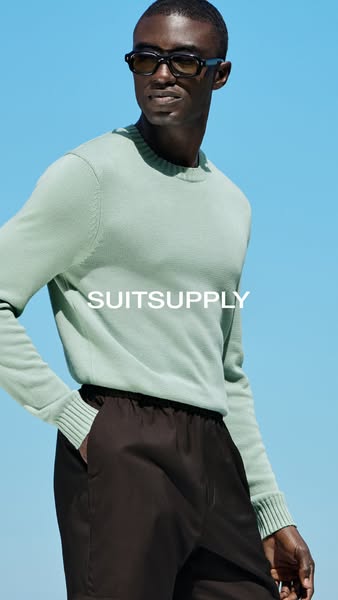 This ad showcases a man wearing a sweater and pants from SuitSupply, against a sky blue background.