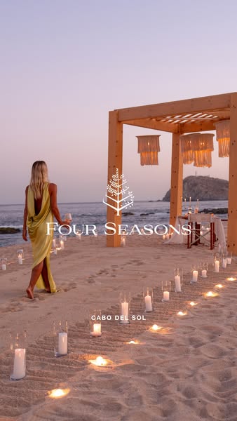 The ad shows a woman in a yellow dress walking on a beach toward a candle-lit wooden structure. The Four Seasons logo is