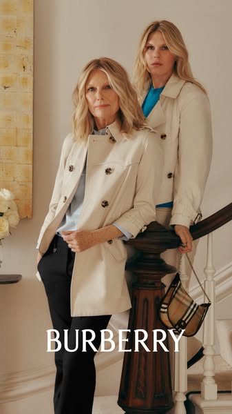 An image ad for Burberry featuring two women in Burberry trench coats standing in a stairway.