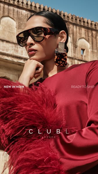 This ad for CLUB L London features a model in a red dress with a feathery trim, accessorized with sunglasses and stateme