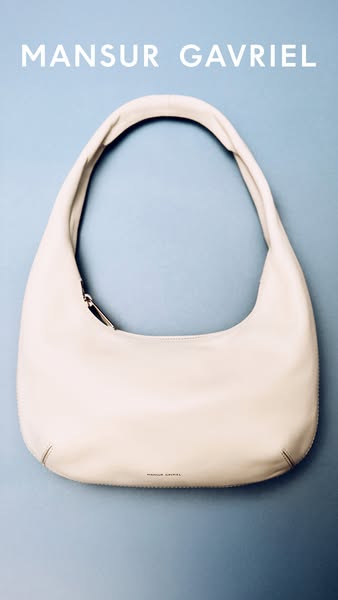 This image ad showcases a white Mansur Gavriel hobo bag against a blue background. The focus is solely on the bag, highl