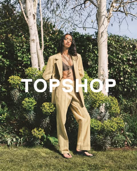 This ad features a woman outside in a garden setting wearing a striped pants suit and bra top from Topshop.