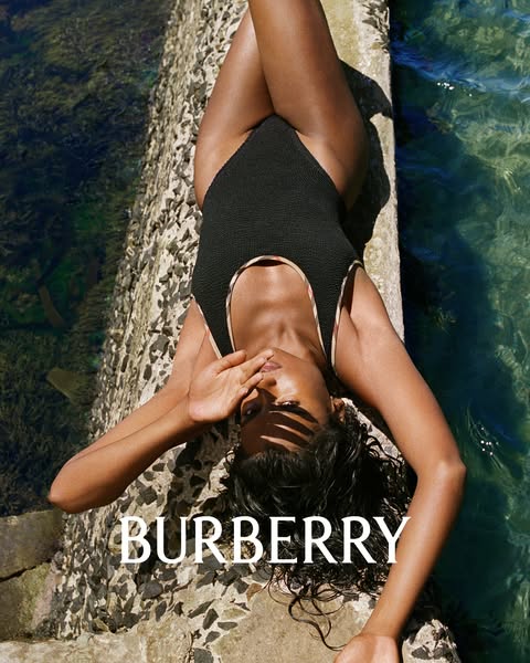 This ad features an image of a model wearing a Burberry swimsuit, set against an outdoor, poolside backdrop. The layout