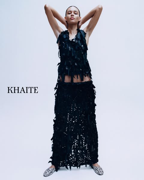 This is a fashion advertisement for Khaite. It features a single model wearing a black two piece dress made out of ribbo