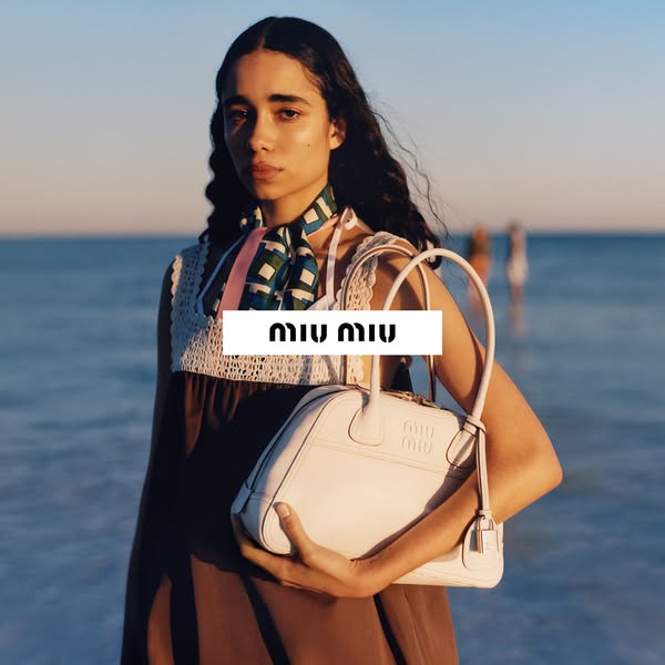 This ad features a model holding a handbag from Miu Miu while standing on a shoreline.