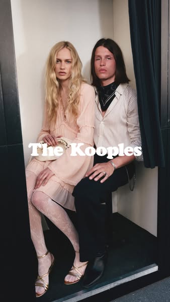 A striking image ad for The Kooples featuring a male and female model seated together in what appears to be a photo boot