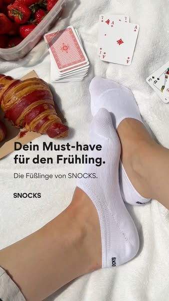 This ad for Snocks socks features a flatlay including cards, croissants, strawberries and the advertised product.