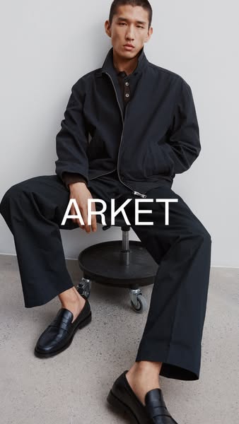 An image ad showcasing a man wearing a jacket, shirt, trousers, and loafers, all by the brand Arket.