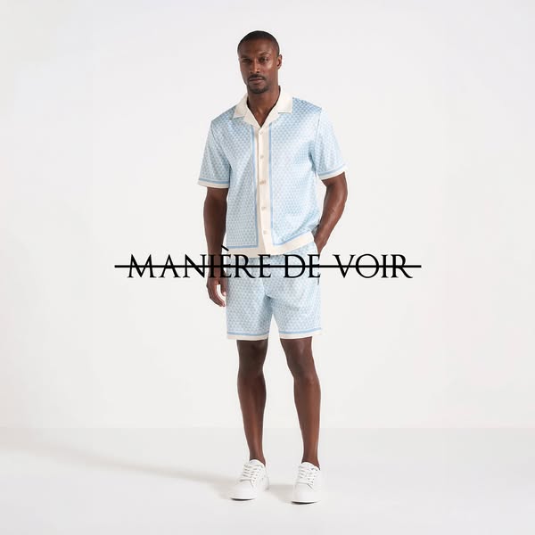 This ad features a black male model showcasing a matching blue top and bottom set from the brand Maniere De Voir. The ad
