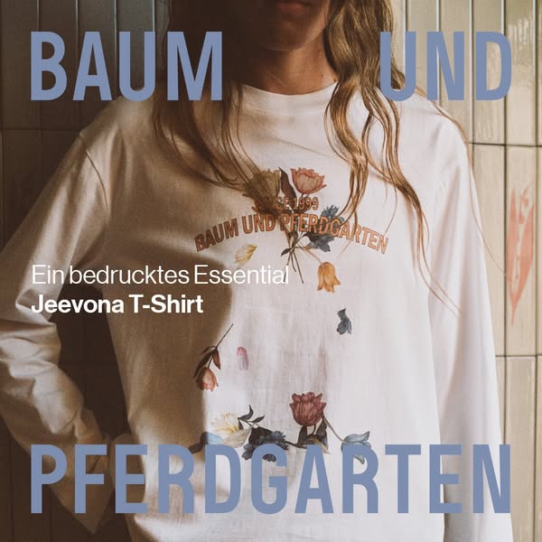 This image ad showcases the Baum Und Pferdgarten brand by featuring a white long-sleeve shirt with a floral design. The 