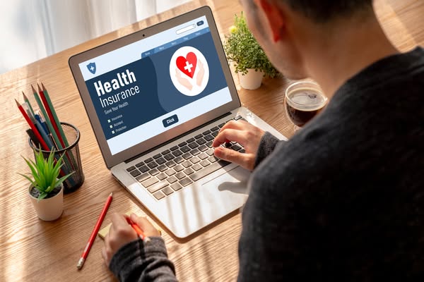 The ad features an image of a person working at a laptop and shows an ad for health insurance, which includes a click bu