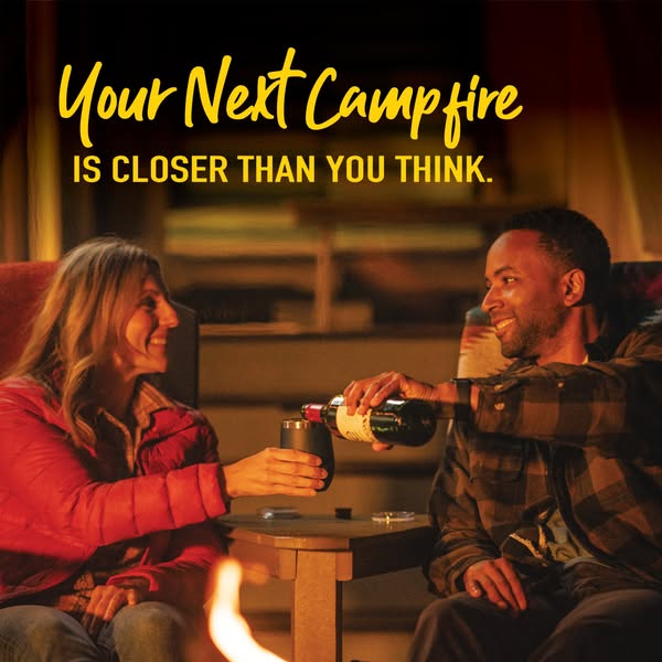 An image ad showing a man and woman enjoying wine by a campfire, with the headline 'Your Next Campfire is Closer Tha
