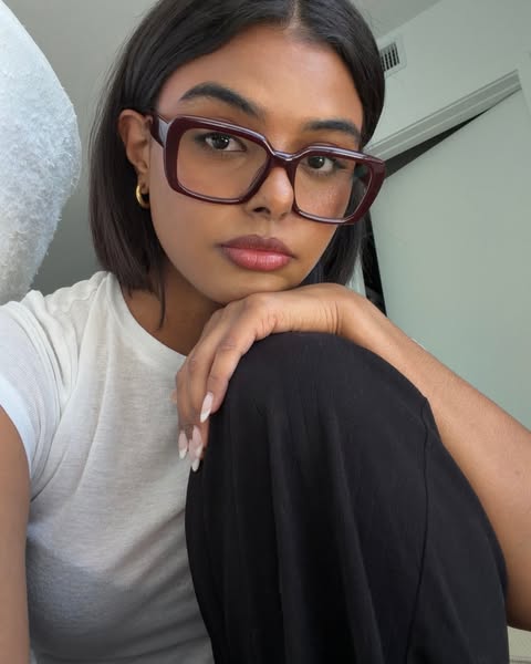 The ad features a woman wearing maroon-colored, thick-framed glasses. The ad is likely for eyewear.