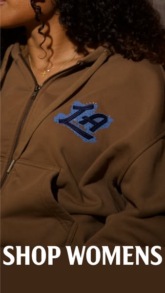 A close up image of a woman wearing a zipped up brown hoodie. The ad promotes the sale of women's wear.