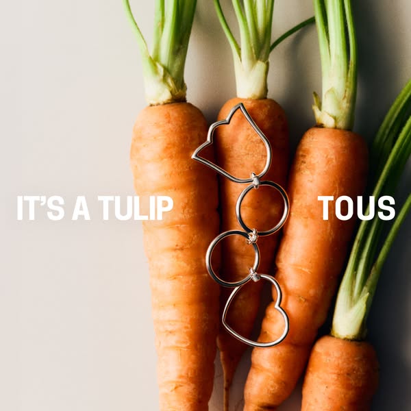 This ad showcases a Tous necklace by photographing it draped on a bunch of carrots. The text reads, 'It's a tuli