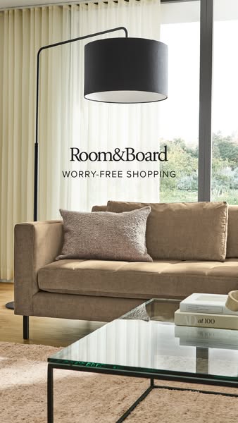 This image ad promotes Room & Board furniture. The image focuses on a living room setup including a sofa, coffee tab