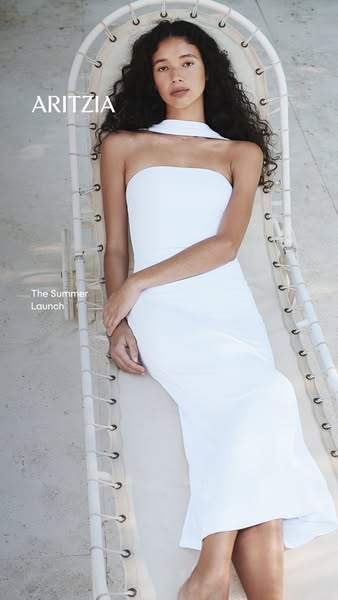 A woman in a white dress reclines on a white mesh chair. The ad promotes the Summer Launch from Aritzia.