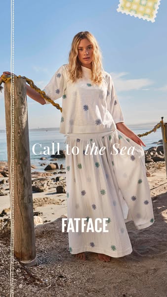 This ad features a young woman on a beach, modeling a matching patterned white top and wide-legged pants from FatFace. T