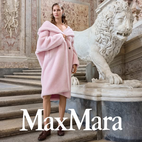 This ad showcases a woman wearing a pink Max Mara coat in a marble-filled building.