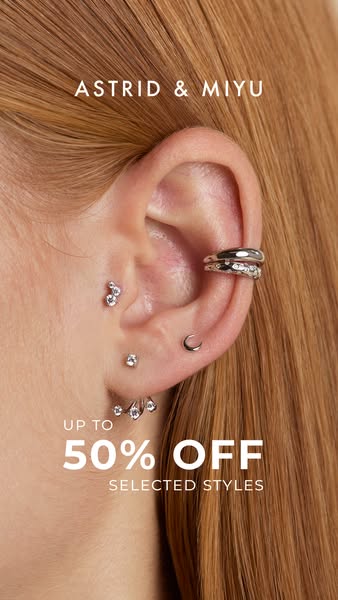 This ad is for Astrid & Miyu jewelry and features an ear with multiple piercings wearing different silver-colored ea