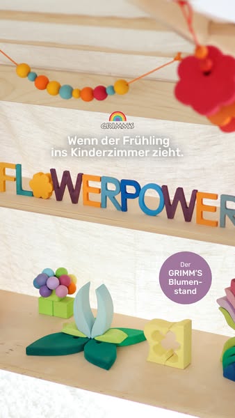 This image ad showcases Grimm's wooden flower block sets in an indoor setting. The primary message is conveyed throu