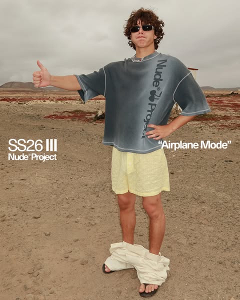 This ad features an image of a model in a desert-like setting, wearing clothing by Nude Project. The brand and product a