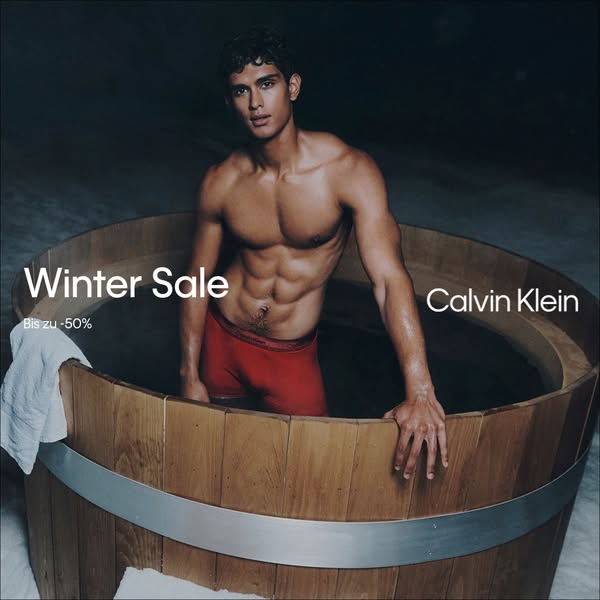 This image ad for Calvin Klein features a shirtless man in red underwear sitting in a wooden tub. The ad promotes a wint