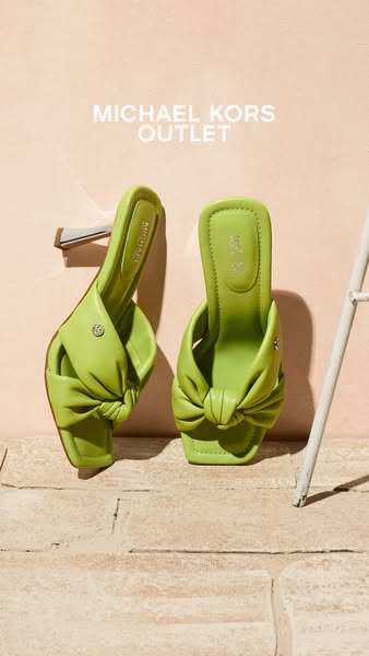 This ad showcases lime green Michael Kors Outlet heeled sandals against a peach background and textured floor.