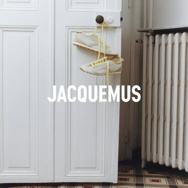 This ad showcases a pair of Jacquemus sneakers hung by their laces from a door handle. The brand name appears prominentl