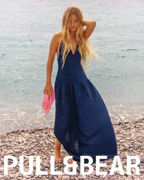 This image ad features a woman posing on a rocky beach in a flowy dress with visible branding for Pull&Bear. The ad 