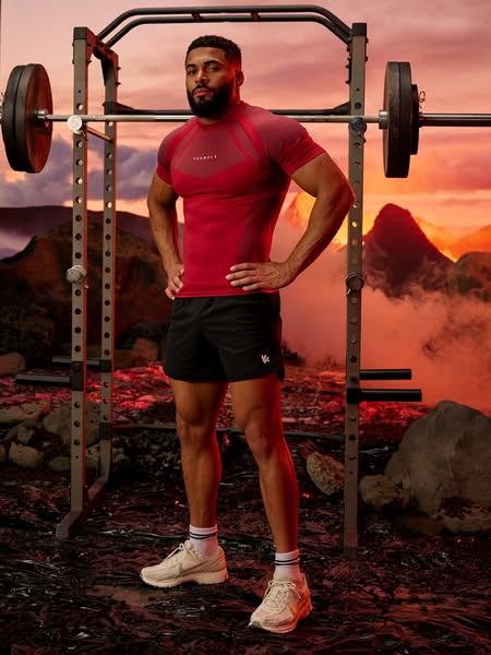 An image ad for a workout clothing brand. A man is shown standing next to gym equipment while wearing the brand's ap