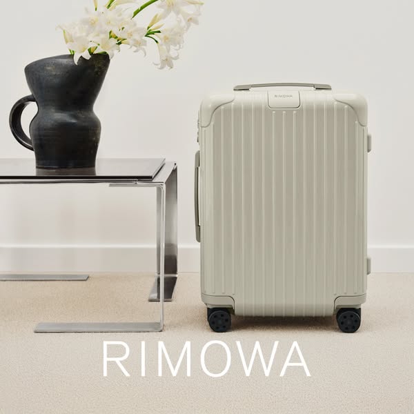 This ad showcases a RIMOWA suitcase in a neutral setting, emphasizing its design and quality.