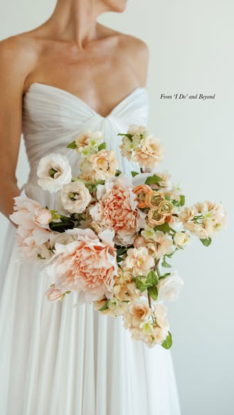 This image ad showcases a bride holding a peach-colored flower bouquet. The overall feel of the image is soft and romant