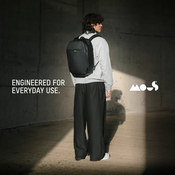 This ad showcases a minimalist black backpack in a studio setting with a model to demonstrate its wearability for everyd
