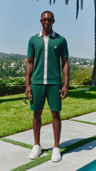This ad features a man modeling an emerald green matching polo shirt and shorts set with white sneakers, set against a b