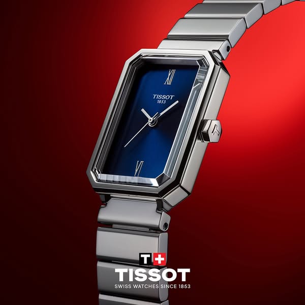 This ad showcases a Tissot watch against a red background. The watch has a silver band and a blue face. The Tissot logo 