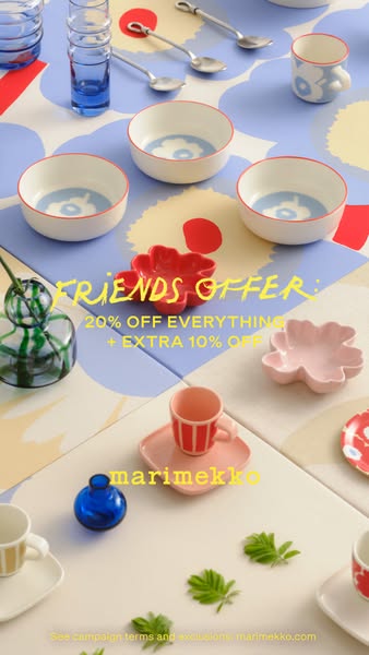 An overhead shot of Marimekko homewares, including bowls, mugs, and vases, laid out on a patterned surface with a Friend