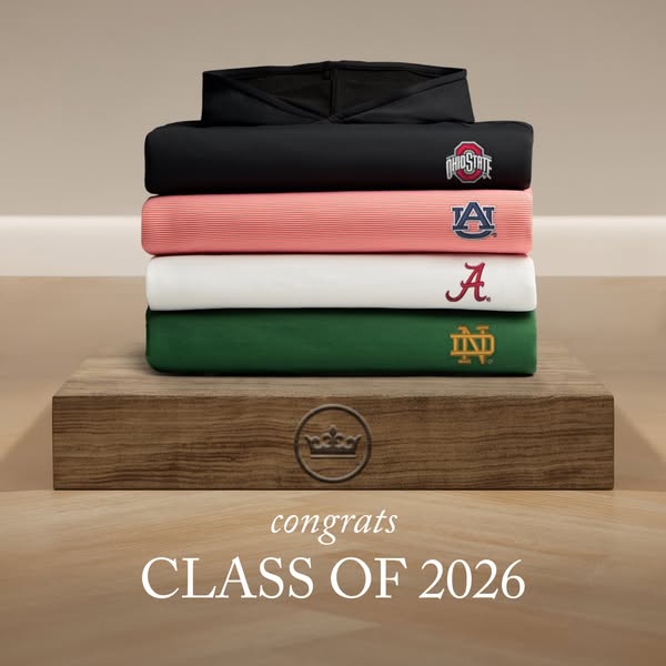 The image is focused on a stack of folded, school-branded polos on a wooden surface. The text is congratulating the clas