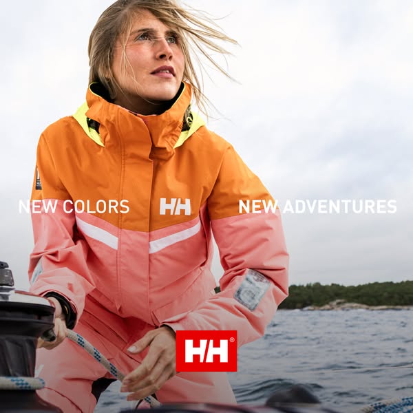 An image ad for Helly Hansen apparel. A woman on a boat wearing a waterproof jacket. The jacket has a salmon-colored bot