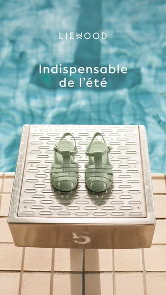 A close up of a pair of sandals on a diving board with a pool in the background.